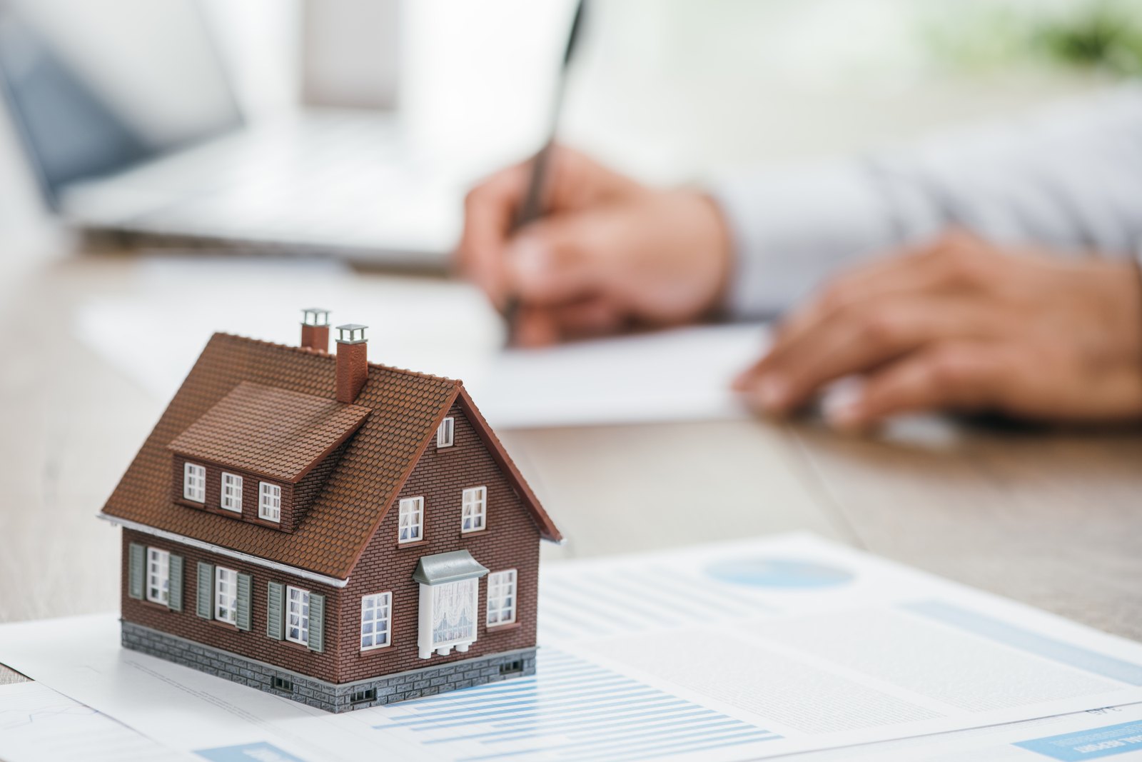 An appraiser signing a property appraisal report beside a model house